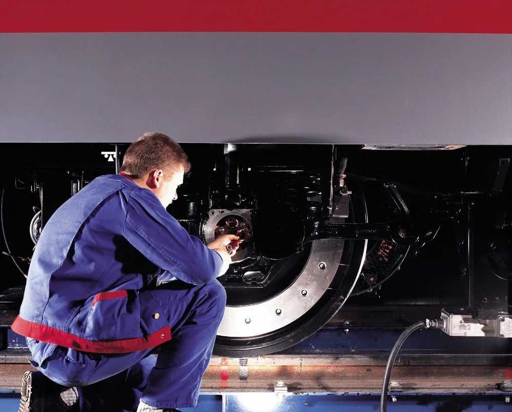 Techniker arbeitet unter einem Zug in einer Werkstatthalle.