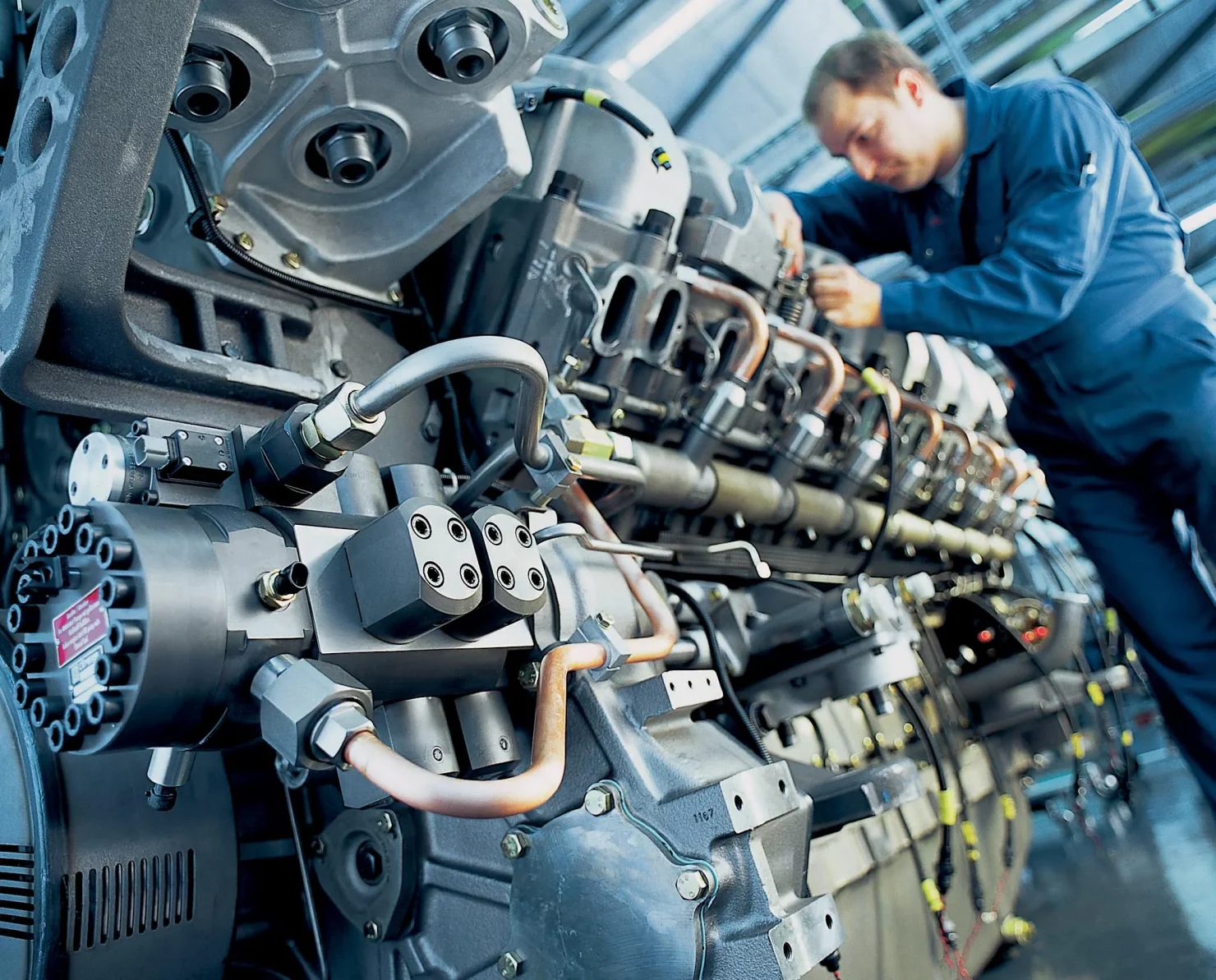 Mechaniker überprüft eine große Motoranlage in einer Produktionshalle.