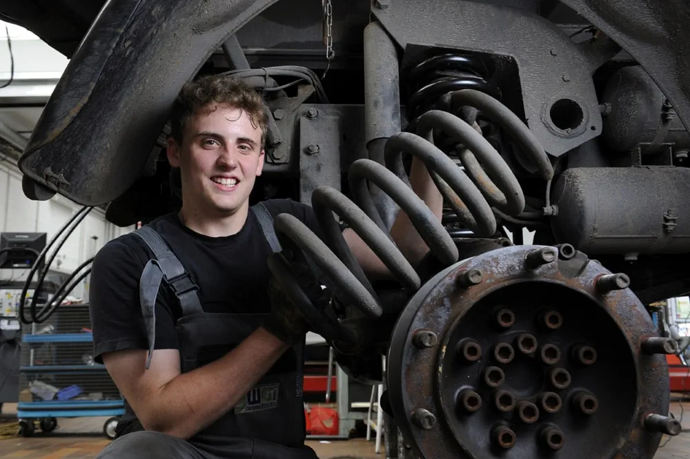 Mitarbeiter repariert ein mechanisches Teil eines Zuges in einer Werkstatt.