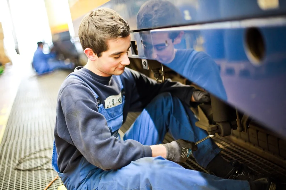 Techniker überprüft die Seitenverkleidung eines Zuges in einer Werkstatt.