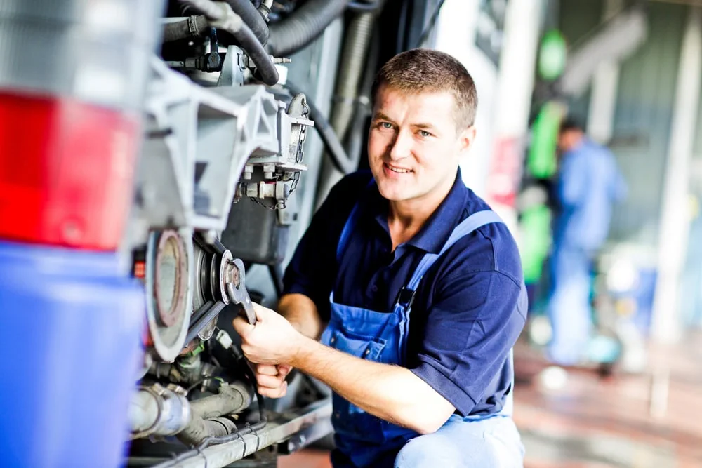 Mitarbeiter kontrolliert Zugräder in einer Werkstatt mit Hebebühne.