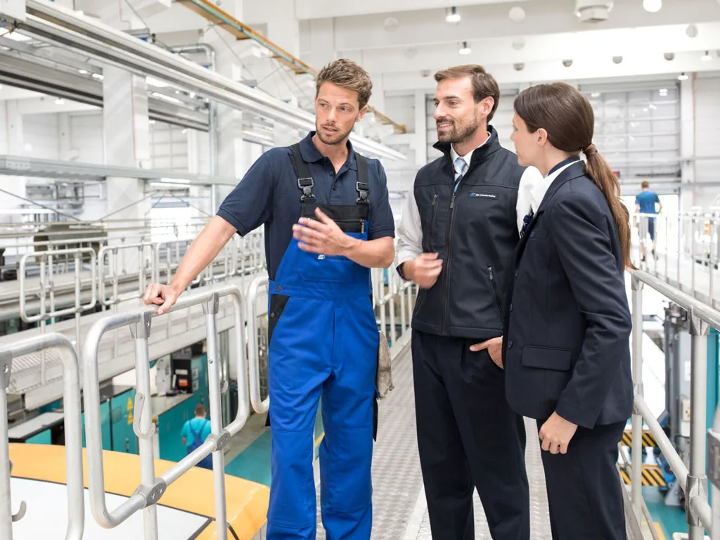 Mitarbeiter in der Instandsetzungshalle diskutieren technische Arbeiten an einem Zug.